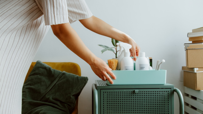 A person organizing cleaning supplies on a teal cart, symbolizing the organization needed for self-employment tax preparation.