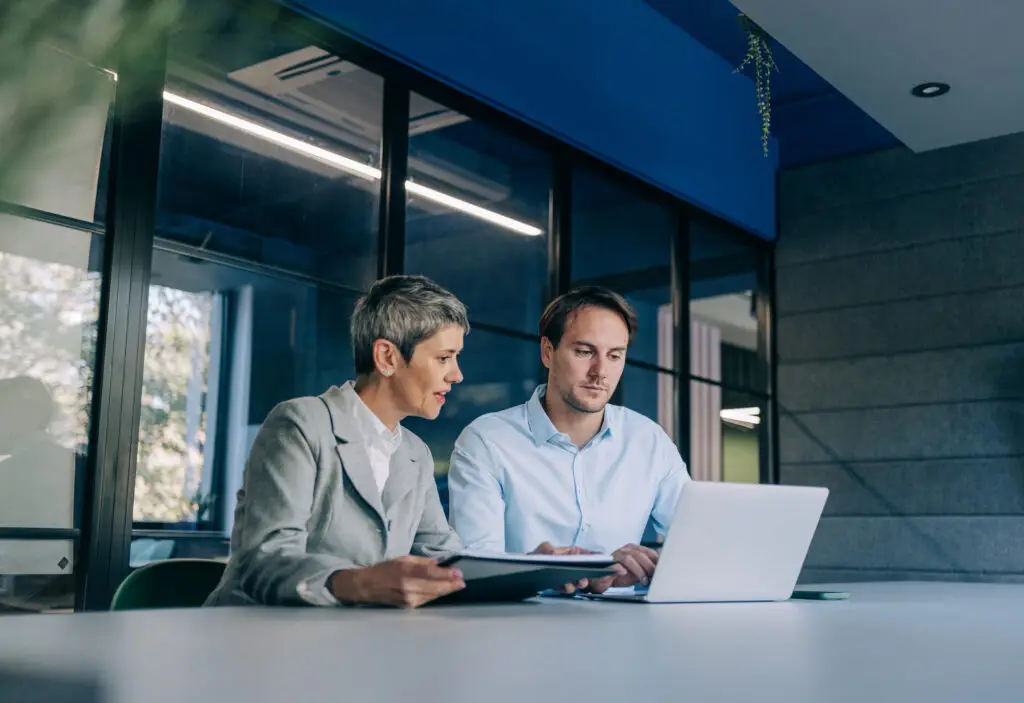 Shot of two confident business persons on meeting in the office. Shot of businessman and businesswoman in meeting at the office. Business couple discussing important documentation in the workplace. Two business people in office working on business reports.