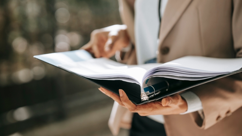 A person holding a folder with opened pages, pointing at the Sorren tax solutions.