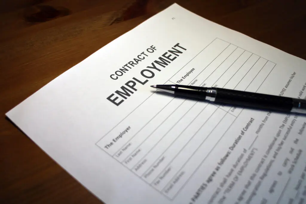 A photo of someone filling out a Contract of Employment.