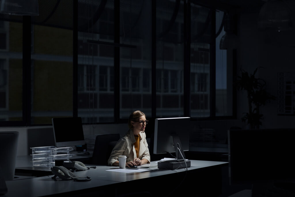 Young businesswoman using computer in dark office.